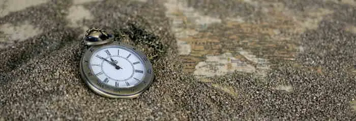 Golden pocket watch in sand.